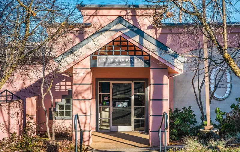 The pink Sheridan Smiles building on South Auburn Street, with the Linda D. Sheridan DDS sign over the entrance